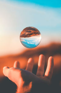 Person hand against sky during sunset