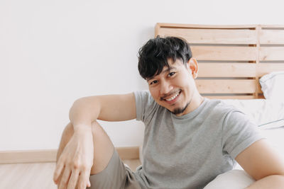 Portrait of smiling young woman sitting on wall at home