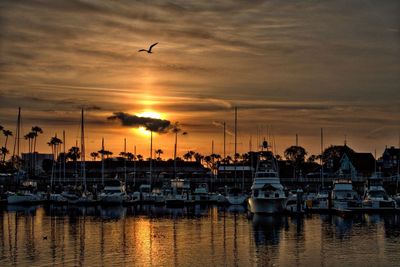 Boats moored at harbor during sunset