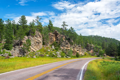 Empty road leading towards trees covered mountains