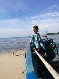 Portrait of smiling girl standing on beach against sky