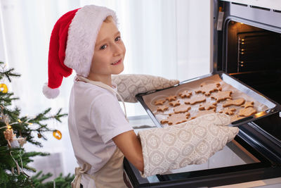 Smiling boy putting cookies in oven