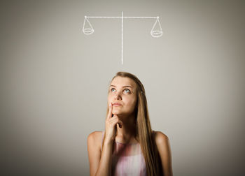 Portrait of young woman looking up against white background