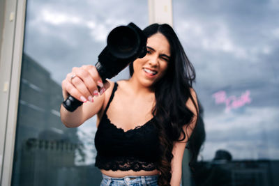 Portrait of smiling young woman standing against sky