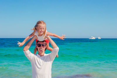 Portrait of young woman standing at beach against clear sky