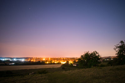 Illuminated city against clear sky at night