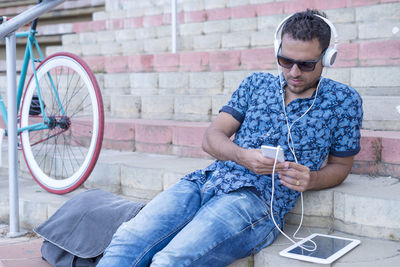 Man listening music while sitting on steps