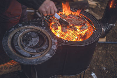 Winter camping. grilling meat over an open fire on a wood stove in the outdoors.