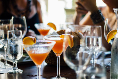 Midsection of friends sitting by martinis on table at restaurant