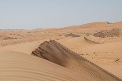 Sand dunes in desert against clear sky