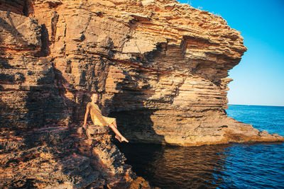 Rock formation by sea against sky