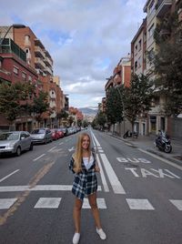 Woman standing on the crossing on the street with a view of the city behind