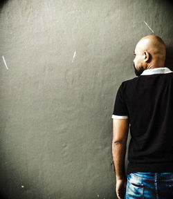 Rear view of man with shaved head against wall