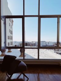 Table and chairs against sky seen through glass window