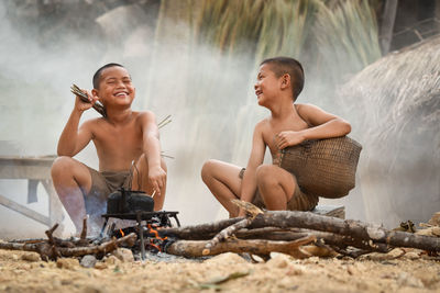 Smiling friends sitting by campfire