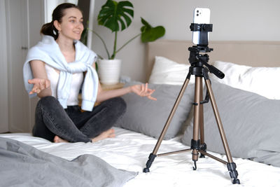 Portrait of young woman sitting on bed at home