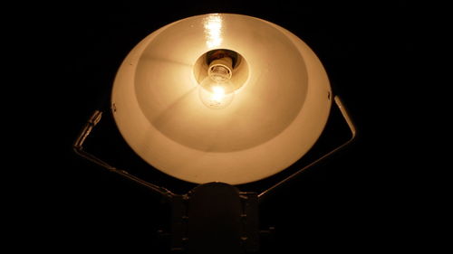 Low angle view of illuminated light bulb against black background