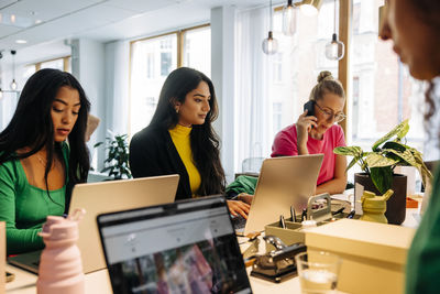Businesswomen working together on laptops at desk in office