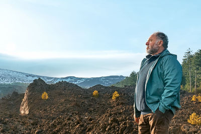 Mature man enjoying freedom, while admiring panoramic view of snowy summits of active volcano etna.