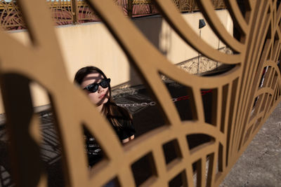 Young woman wearing sunglasses by fence
