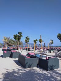 Chairs by swimming pool against clear blue sky