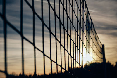 Close-up of fence against sunset sky