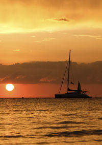 Silhouette sailboat sailing on sea against sky during sunset
