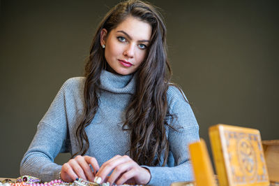 Reflection of a woman in mirror choosing and trying different jewelry, soft focus, close-up