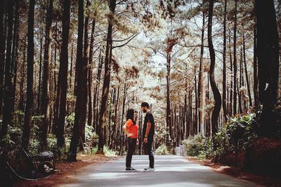 People on road amidst trees in forest