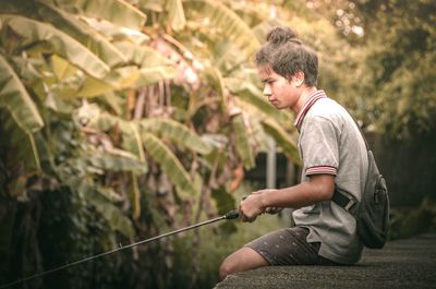 Side view of young man looking at plants