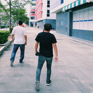 Rear view of men walking on footpath