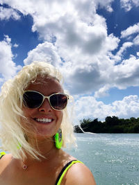 Be happy portrait of smiling woman wearing sunglasses against sky