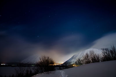 Scenic view of snow covered mountains against sky at night