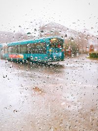 Bus on street seen through wet glass window during rainy season