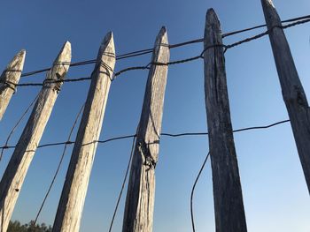 Low angle view of wooden fence against blue sky