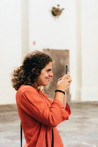 Side view of young woman holding mobile phone