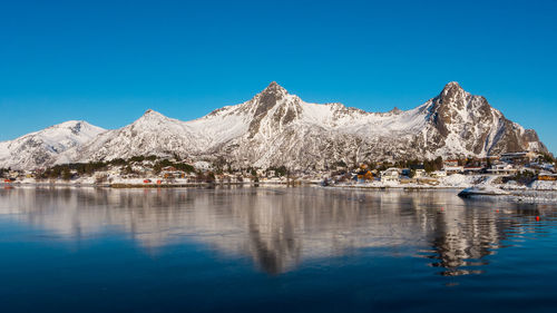 Scenic view of lake and mountains against clear blue sky