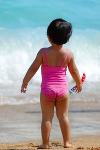 Rear view of boy on beach against sky