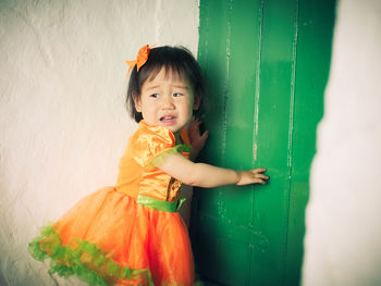 Scared toddler girl standing by door