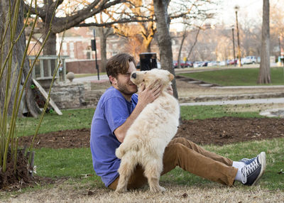 Full length of man sitting with dog