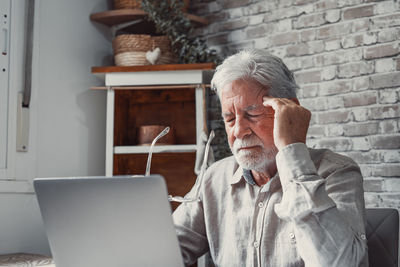Side view of man using laptop while sitting on table