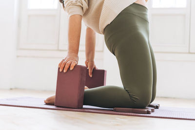 Attractive middle aged woman in sportswear ptactice yoga with equipment in light studio