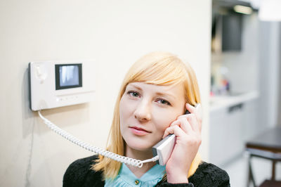 Close-up portrait of young woman talking on phone at home