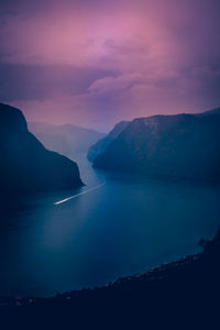 Scenic view of lake amidst mountains against dramatic sky