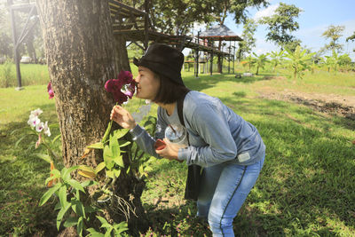 Young woman walking in summer park with flowers.