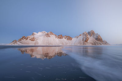 Scenic view of lake and mountains against clear blue sky