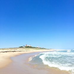 Scenic view of beach against blue sky