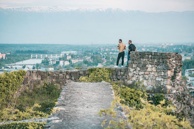 People looking at castle against sky