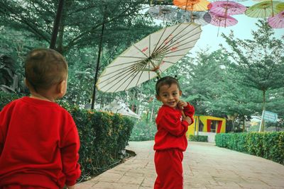 Cute friends playing with umbrella in park