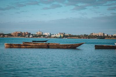 A scenic view of fishing boats against cityscape during sunset